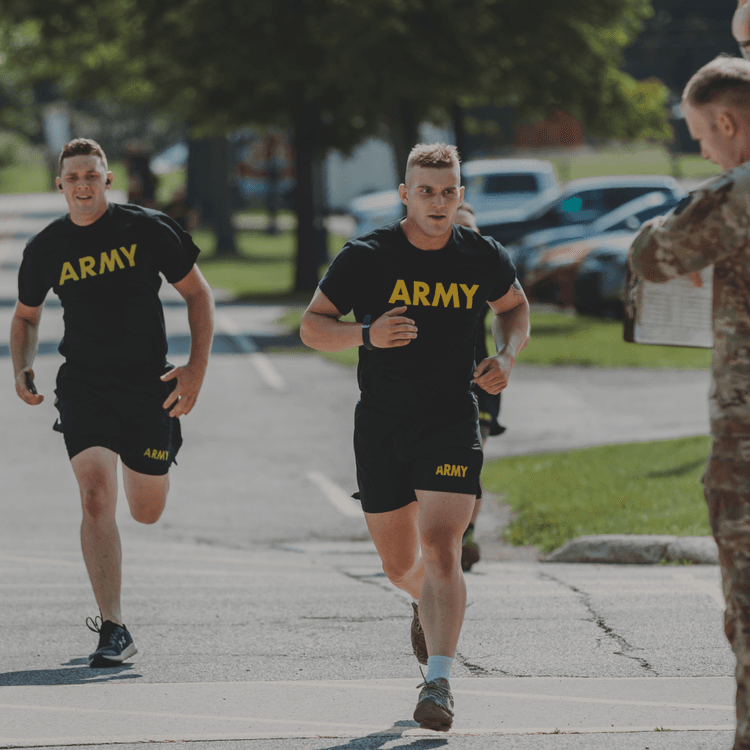 Soldiers in black Army tees run past instructor during outdoor fitness test.